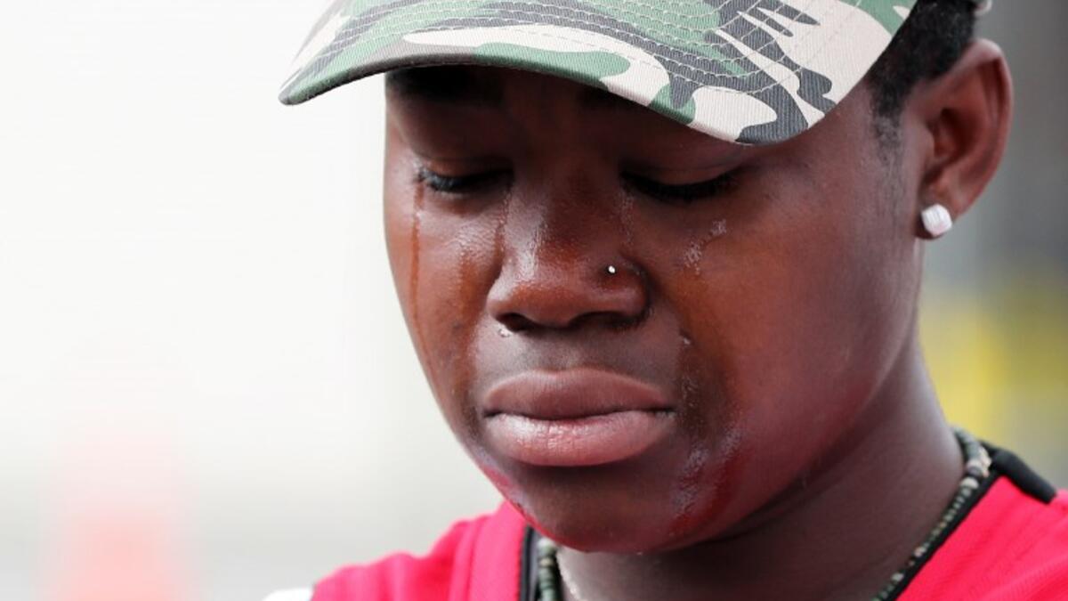 A young mourner weeps after placing flowers at the police cordon as Police conintue the search of the area close by the Linwood Ave Mosque in Christchurch 
MICHAEL BRADLEY / AFP