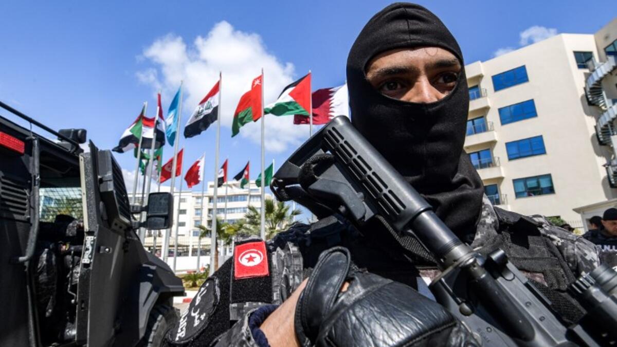 A member of the Rapid Intervention National Brigade (BNIR) of the Tunisian security forces standing guard by the national flags of the Arab League member states, outside Council of Arab Interior Ministers' headquarters, ahead of the Arab League summit due to take place in Tunis. 
FETHI BELAID / AFP
