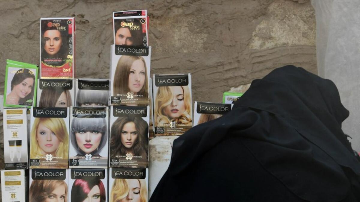 A fullly-veiled woman checks hair dye packages displayed on a stall  in the souk or market of Al-Hol camp for displaced people in northeastern Syria
GIUSEPPE CACACE / AFP