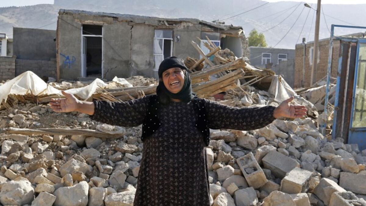 An Iranian woman gestures next to the rubble of her home in Kouik village.

(ATTA KENARE / AFP)