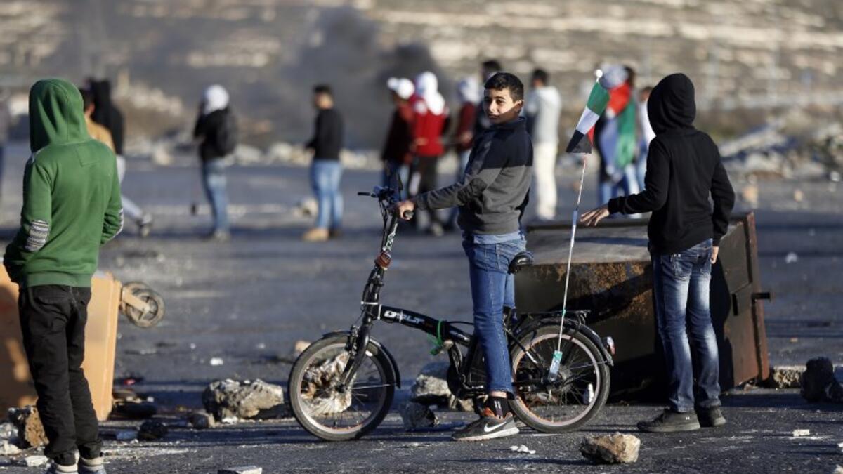 A Palestinian boy rides his bike during clashes with Israeli forces near an Israeli checkpoint in the West Bank city of Ramallah.
(ABBAS MOMANI / AFP)