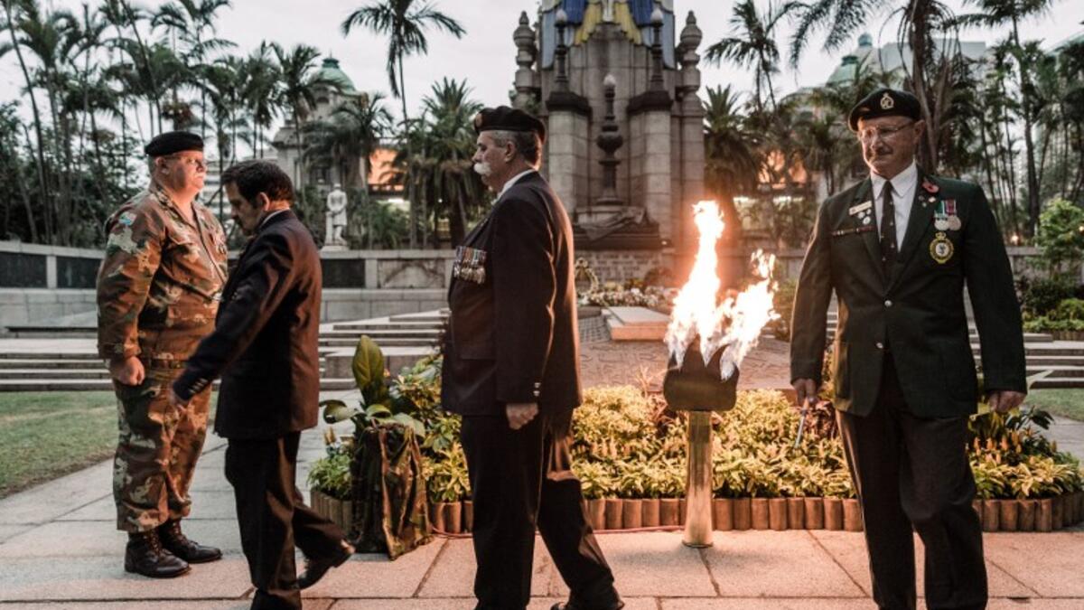 Staff Officers from Defence Reserves of the South African National Defence Force (SANDF) light a gas lamp lit for the Beacon of Light at the Cenotaph in Durban, on November 11, 2018 as part of commemorations marking the 100th anniversary of the 11 November 1918 armistice, ending World War I. 
RAJESH JANTILAL / AFP