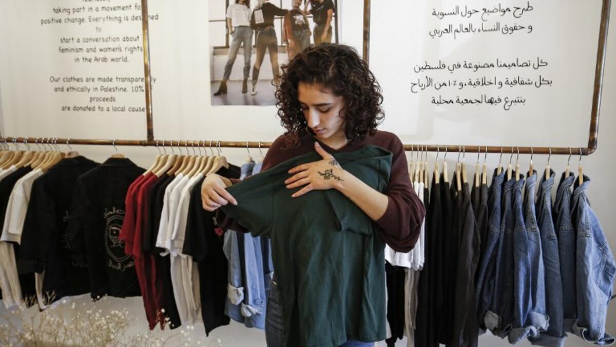 Palestinian fashion designer Yasmeen Mjalli speaks while standing in her clothing shop where her label collection "BabyFist" carrying anti-sexual harassment slogans is showcased, in Ramallah 
ABBAS MOMANI / AFP