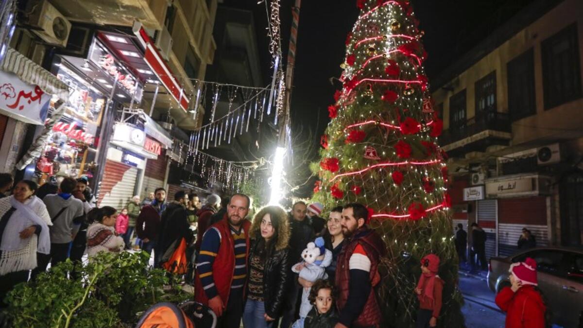 Syrians pose for a picture as they gather around a Christmas tree in the capital Damascus' central neighbourhood of Qassaa on December 21, 2018. 
LOUAI BESHARA / AFP