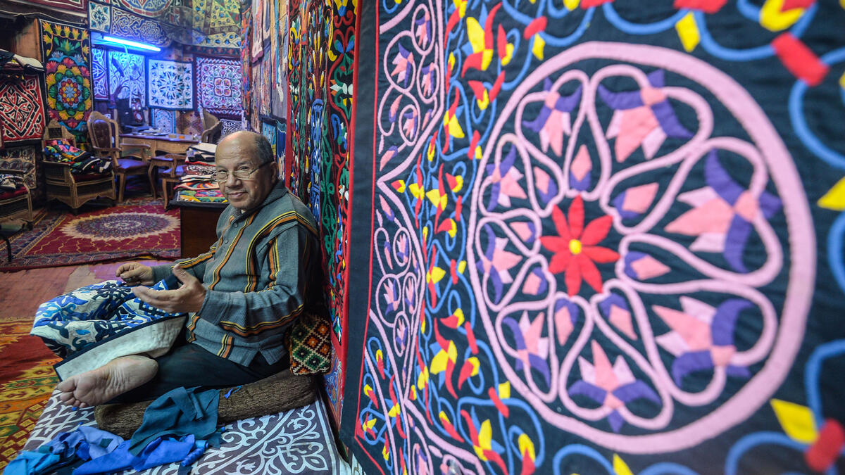 An Egyptian craftsman gestures as he sits while working on a tapestry in his shop in Khayamiya Street, or the Street of Tent-makers, in the old city of the Egyptian capital Cairo 
Mohamed el-Shahed / AFP