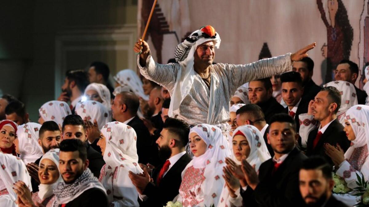 A man dressed in traditional Palestinian clothing dances during a mass wedding ceremony  
Mahmoud ZAYYAT / AFP