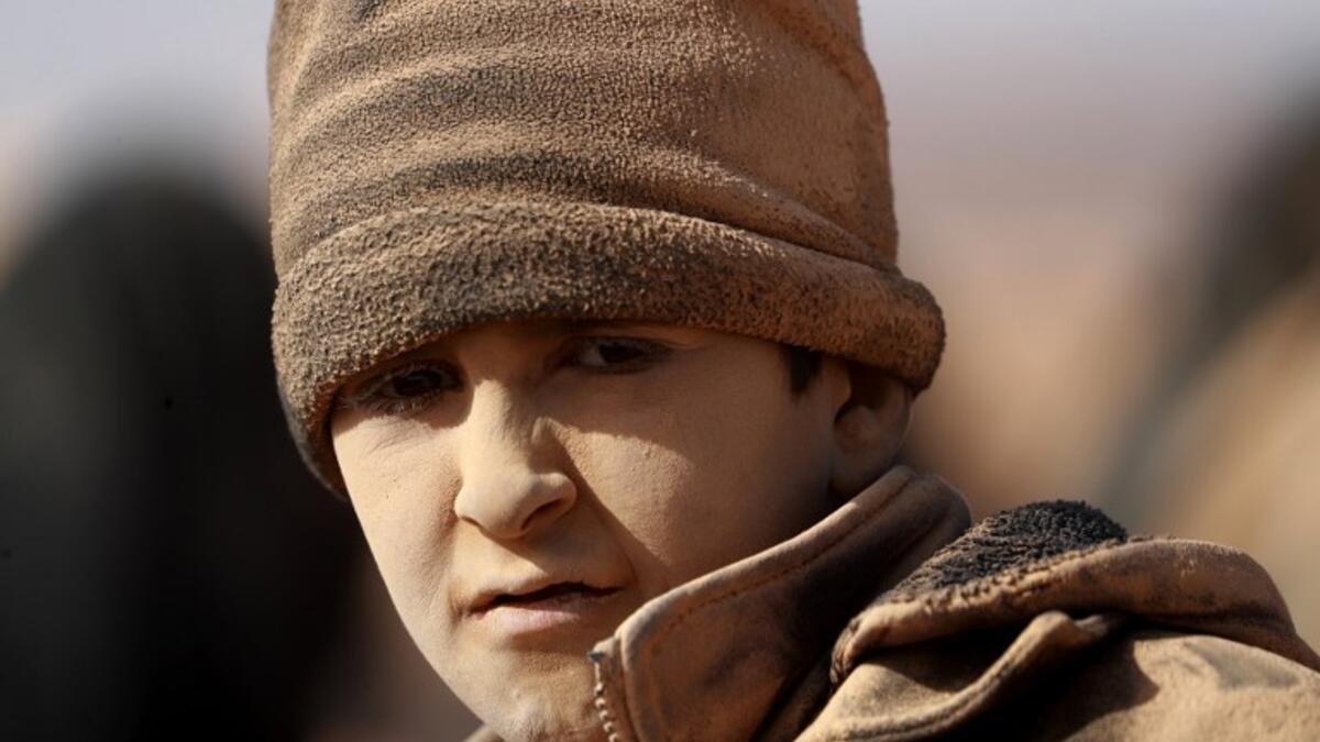 A young boy covered in dust is ppictured as people who fled battles between Syrian Democratic Forces (SDF) and ISIS fighters in the Syrian village of Baghouz, arrive after crossing a desert in the back of a truck to a region controlled by the SFD in the countryside of the Deir Ezzor province  Delil SOULEIMAN / AFP