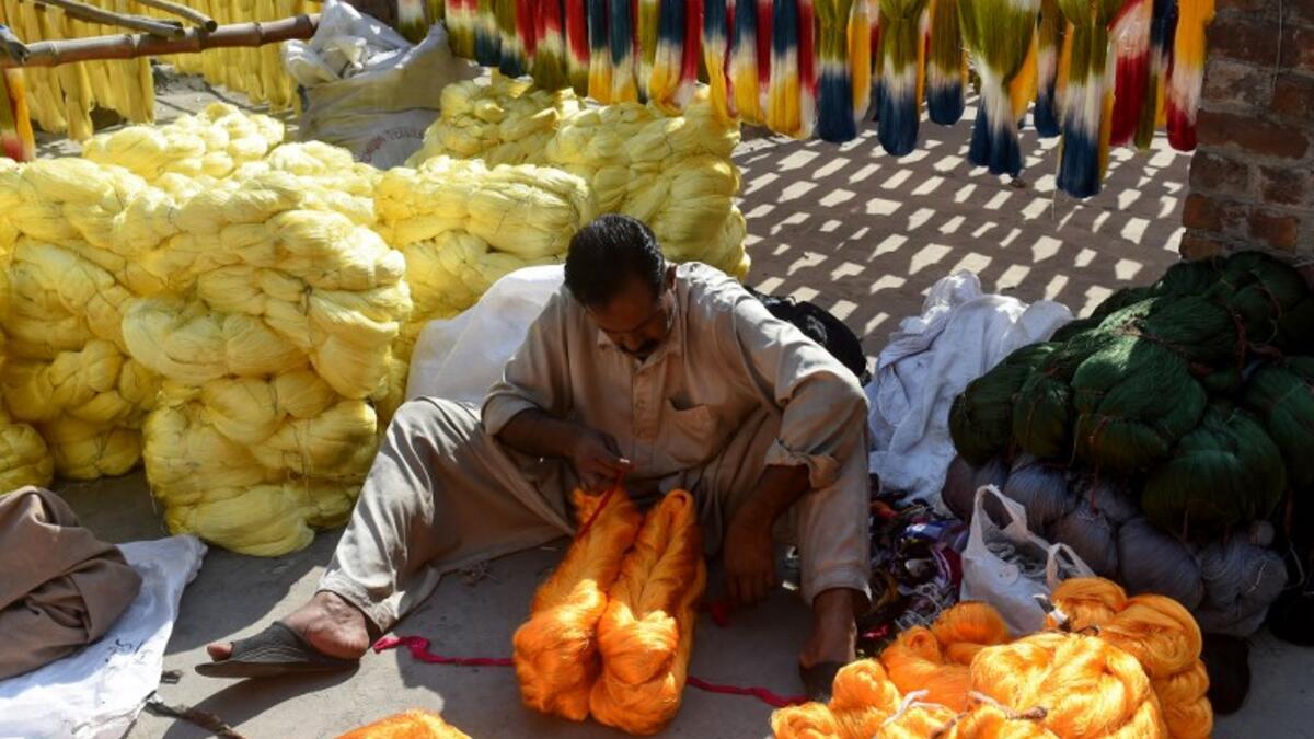 A Pakistani worker collects fabric threads after dyeing at a factory in Lahore on February 11, 2019. 
ARIF ALI / AFP