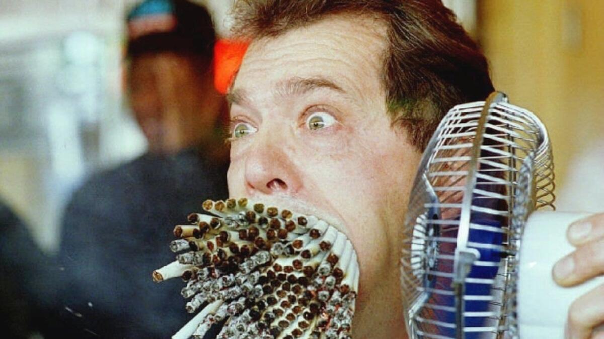 Jim Mouth uses a fan to blow smoke from 155 cigarettes as he breaks “The Guinness Book of World Records” record November 18, 1993 for smoking the most cigarettes at the same time. (AFP/ File Photo)