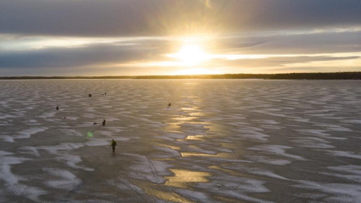 An aerial view shows men waiting near holes drilled into the frozen sea as they ice fish on the Gulf of Bothnia, near Vaasa, Western Finland on December 28, 2018, where winter daylight last for some four hours. 
Olivier MORIN / AFP