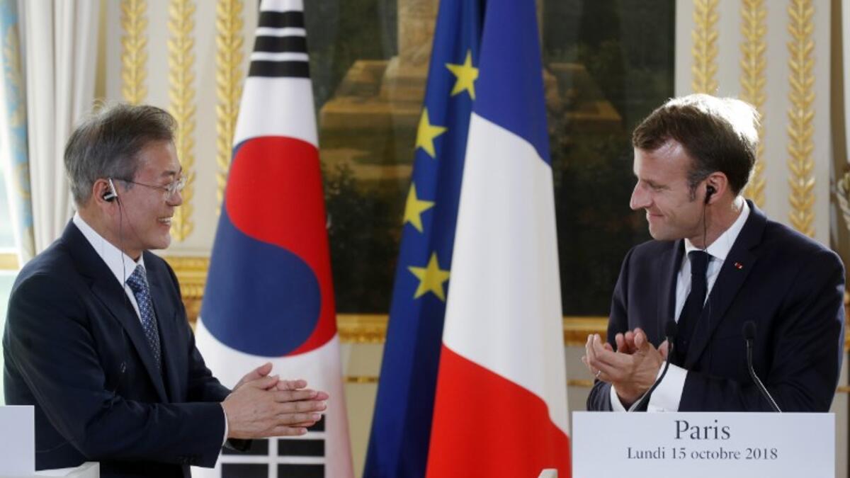 French President Emmanuel Macron (R) and South Korean President Moon Jae-in applaud during a press conference at the Elysee Palace in Paris on October 15, 2018. (PHILIPPE WOJAZER / POOL / AFP)