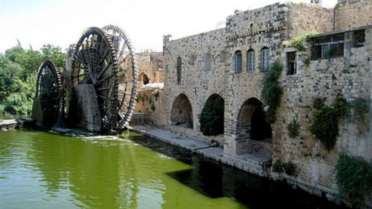 Hama,once the Greco-Roman Epiphania, renamed again Hama, its ancient name restored by Muslim rule, 7th century.
The river, the Orontes ('Assi' in Arabic) runs through it. Hama is known for its characteristic water mills. Visitors today are 
still struck by the evidently obliterated Old City.