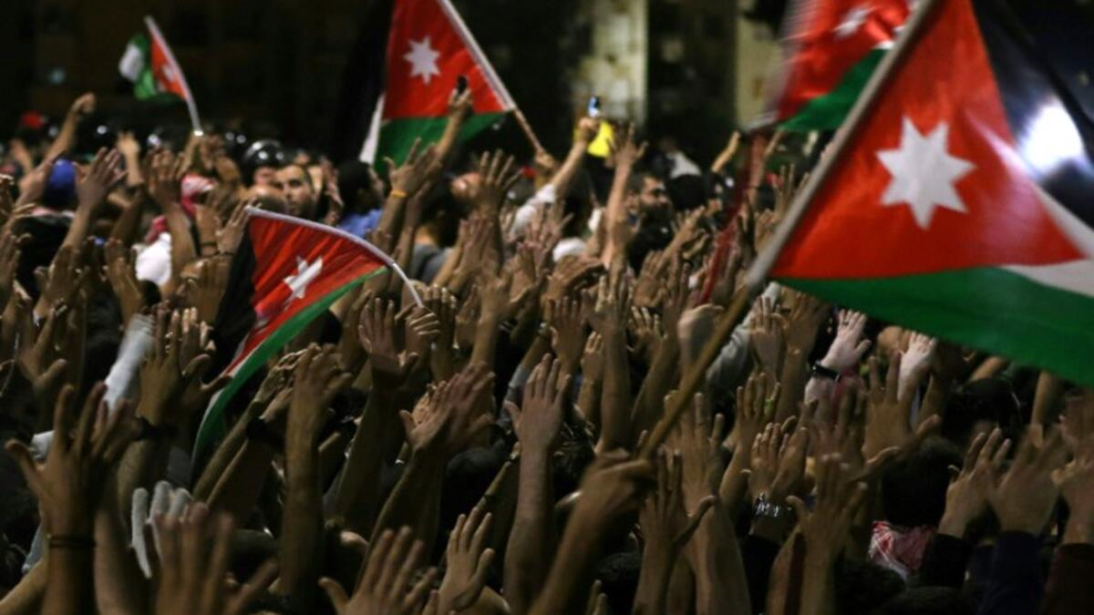 Protesters raise their hands and wave flags near members of the gendarmerie and security forces during a demonstration outside the prime minister's office in the capital Amman late on June 3, 2018. 
Khalil MAZRAAWI / AFP