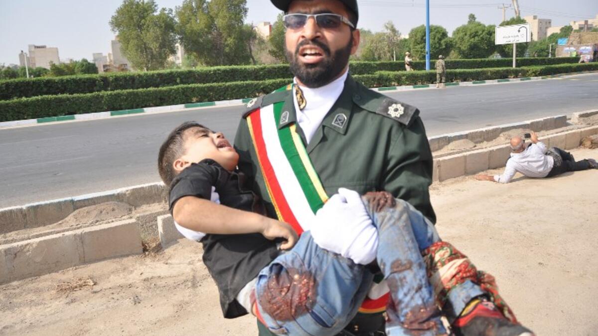 A member of Iran's Revolutionary Guards Corps (IRGC) carrying an injured child at the scene of an attack on a military parade that was marking the anniversary of the outbreak of its devastating 1980-1988 war with Saddam Hussein's Iraq. (Behrad GHASEMI / ISNA / AFP)