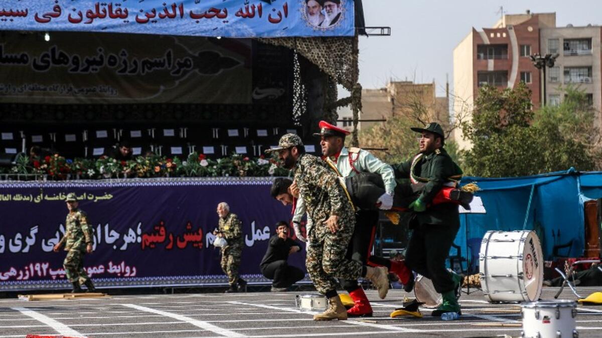 This picture taken on September 22, 2018 in the southwestern Iranian city of Ahvaz shows Iranian soldiers carrying away an injured comrade at the scene of an attack on a military parade that was marking the anniversary of the outbreak of its devastating 1980-1988 war with Saddam Hussein's Iraq. (MORTEZA JABERIAN / ISNA / AFP)