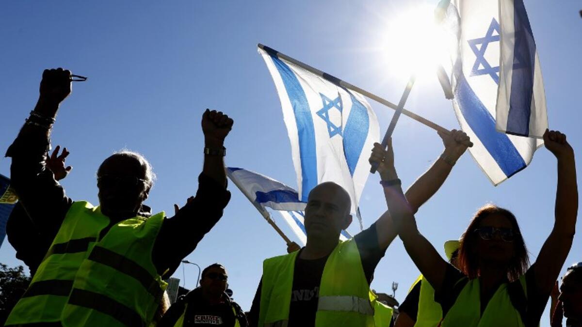 Israeli protesters wearing a yellow vest carry national flags during demonstrations against the rising cost of living on December 14, 2018, in the Israeli coastal city of Tel Aviv. 
JACK GUEZ / AFP