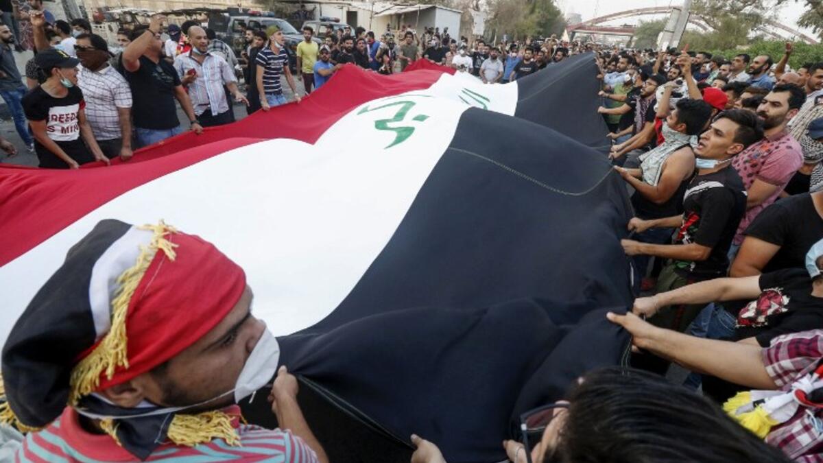 Iraqi protesters chant slogans and wave a large national flag as they gather in a demonstration against corruption and lack of basic services outside the local government headquarters in the southern city of Basra on September 2, 2018. 
Haidar MOHAMMED ALI / AFP