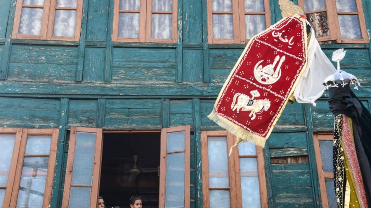 Kashmiri muslim family watches from a window of a residential house as Kashmiri Shiite Muslim mourners flagellate themselves during a religious procession.Tauseef MUSTAFA / AFP