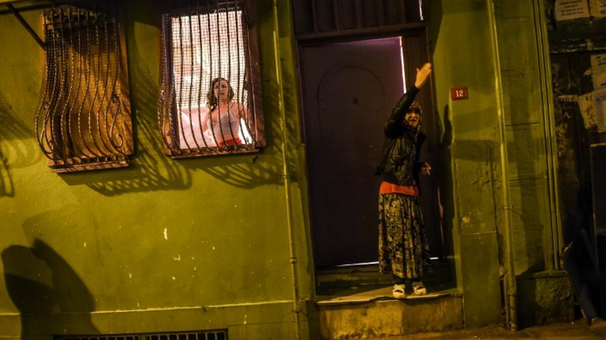 A transgender looks out of a window and a woman reacts as women's rights activists march through Taksim Square to protest against gender violence in Istanbul, on November 25, 2018, on the International Day for the Elimination of Violence against Women. 
BULENT KILIC / AFP