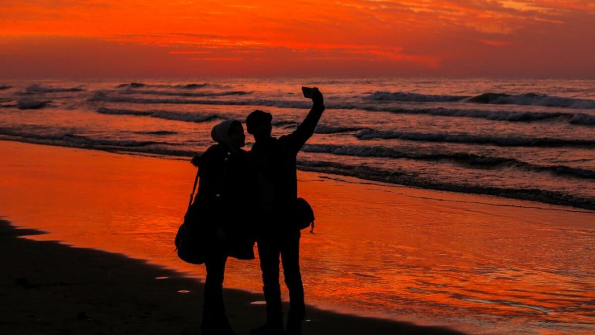 Palestinian people take a picture on the beach at sunset west of in Gaza city on December 31, 2018. 
MAHMUD HAMS / AFP