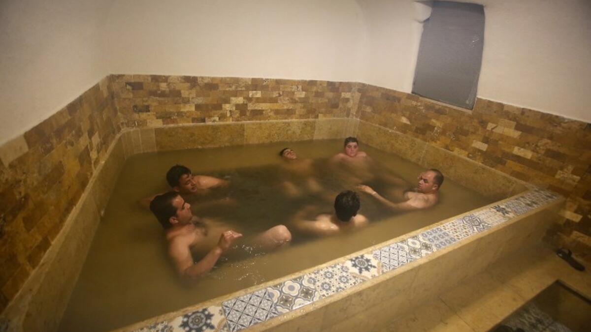 Men sit together in a pool of water at the first traditional Turkish bath (Hammam) opening in the occupied Palestinian West Bank city of Hebron on March 11, 2019. 
HAZEM BADER / AFP