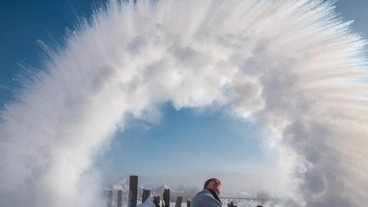 A man from the ladle pours the boiling water up into the sky in an arc in freezing weather. (Shutterstock/ File Photo)
