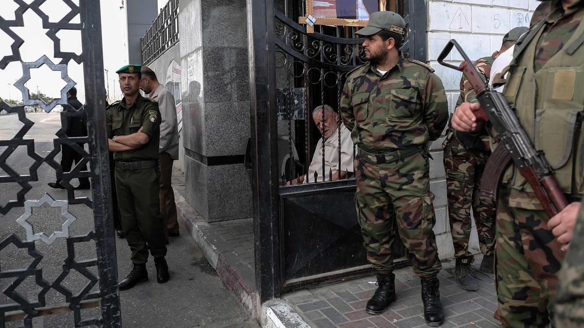 Palestinian security forces loyal to Hamas (right) stand guard outside the Rafah border crossing with Egypt, as security forces loyal to the Palestinian Authority stand guard inside (left), in the southern Gaza Strip. 
Said Khatib / AFP