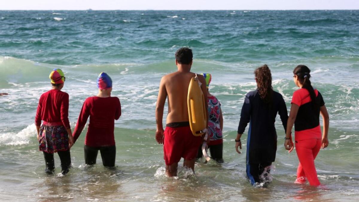 Young Palestinian members of a swimming club, walk into the sea to begin a training session in Beit Lahia. (SAID KHATIB / AFP)