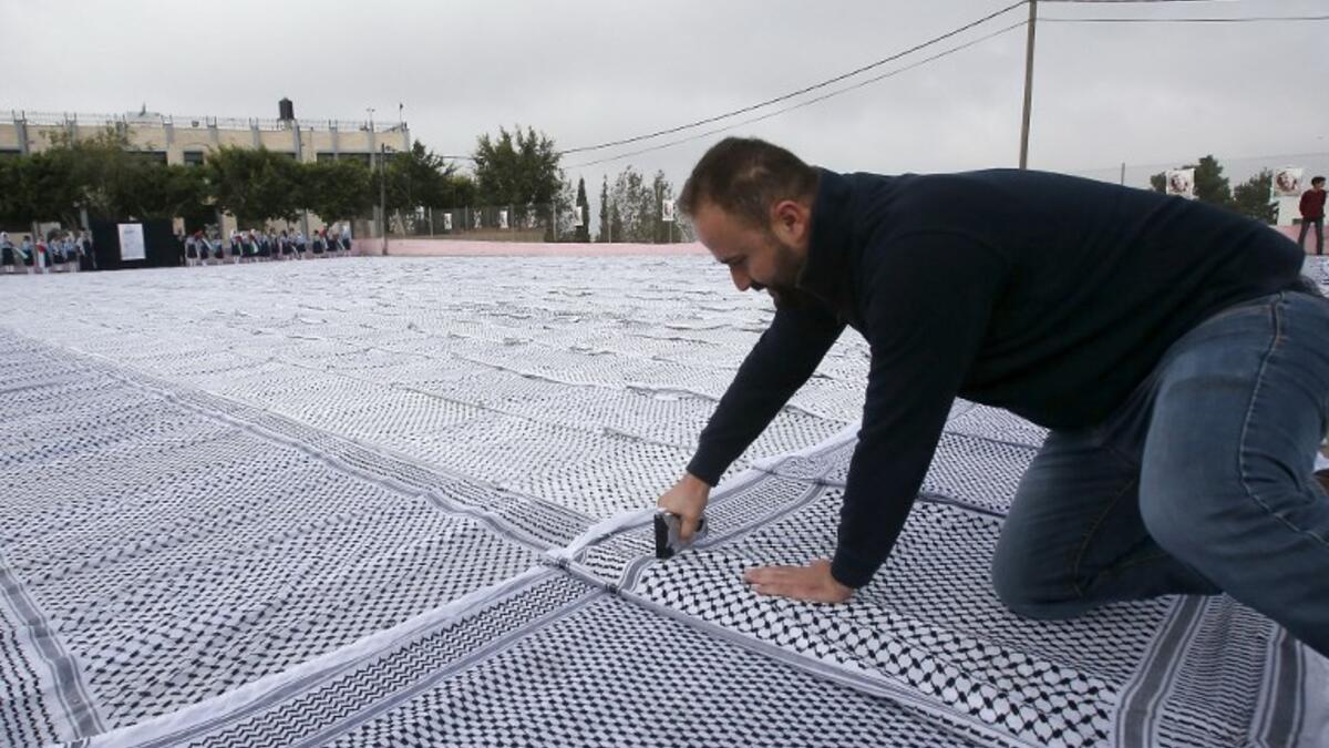 Palestinian students of the Southern Education Direction prepare to apply for the Guinness book of World Records' largest Keffiyeh. (HAZEM BADER / AFP)