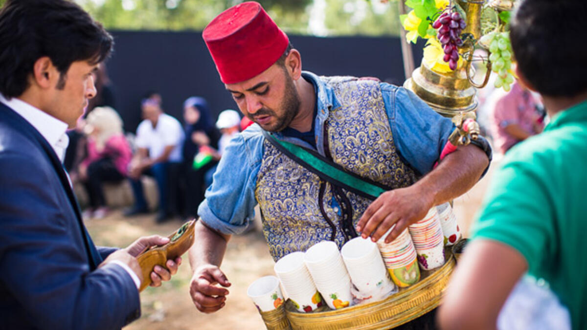 A Jordanian man wearing an Ottoman-style vest and fez, pours iced hibiscus juice for thirsty festival-goers at King Hussein Park on the centennial of the Great Arab Revolt on June 3, 2016.