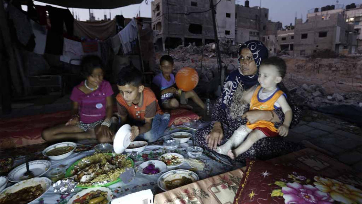 A family in Gaza shares an Iftar dinner during Ramadan. The most popular dish in Palestine is Maqlube, upside-down, which is made with rice, eggplant and meat or chicken, cooked in a pot and flipped up-side down when served. However, due to the situation in Gaza, many families cannot afford buying more than the basic necessities.