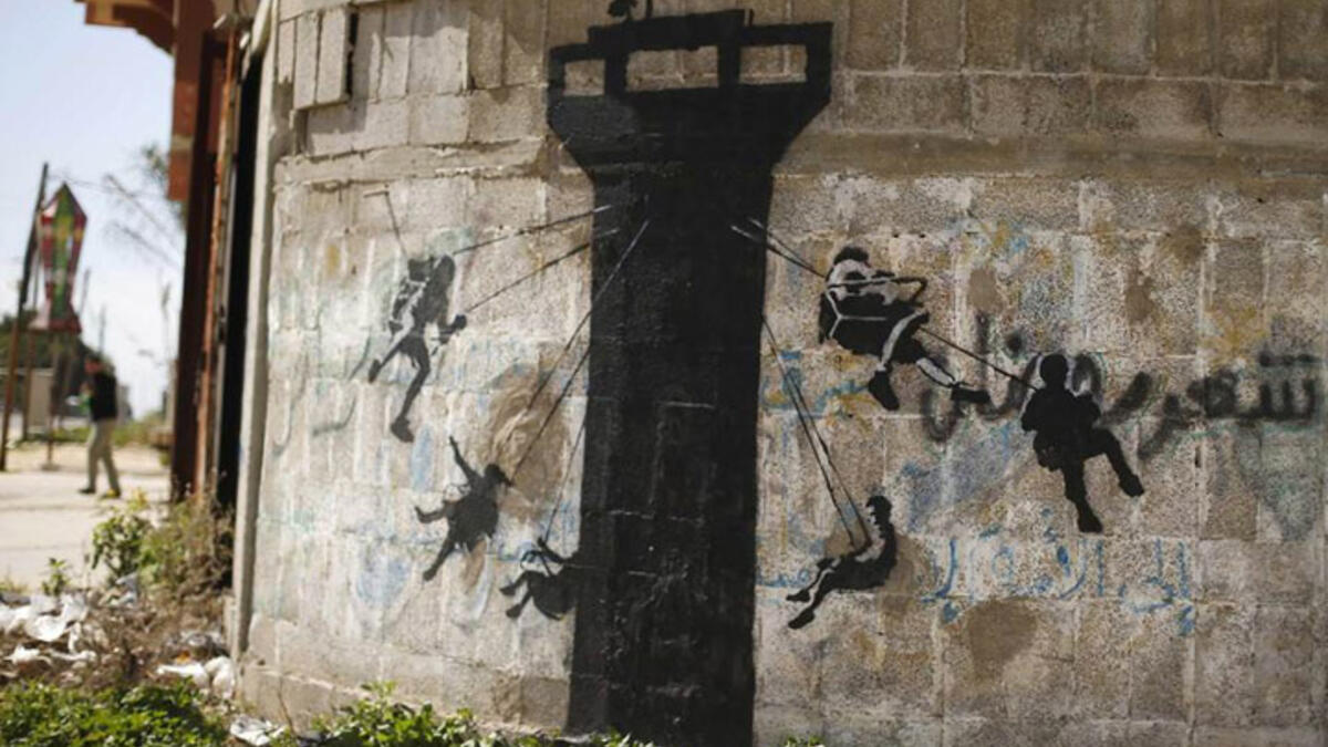 A mural on a wall in Beit Hanoun shows children swinging on a classic Western amusement ride, here done up Palestine style, with an Israeli Defence Forces guard tower planted in its center.