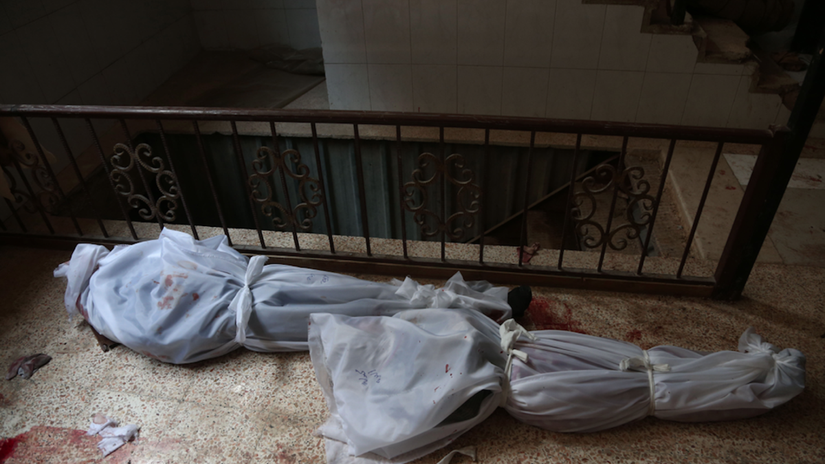 The bodies of civilians who were killed in Syrian army bombardment on the town of Hamouria in the rebel-held enclave of Eastern Ghouta are seen lying on the ground at a make-shift morgue the morning after the attacks on Feb. 20, 2018. 
(ABDULMONAM EASSA / AFP)