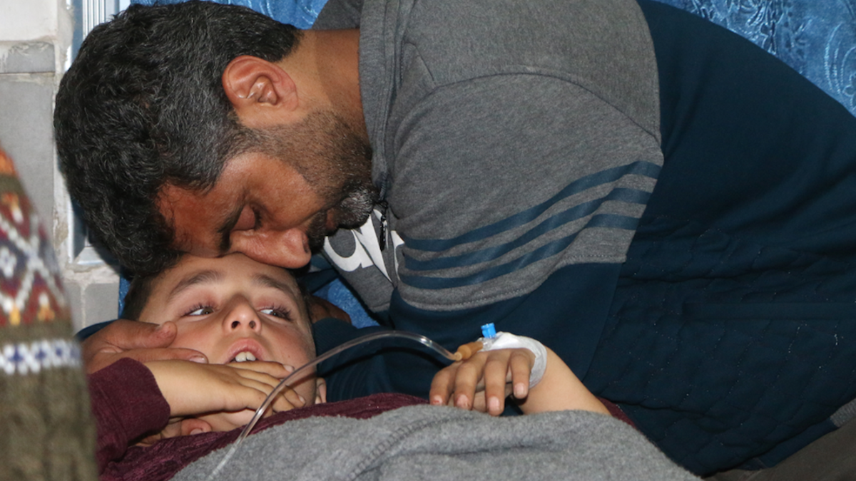 A father comforts his wounded son who was injured in bombardment after he was taken out of intensive care at a hospital in Afrin on Feb. 20, 2018. 
(Ahmad Shafie BILAL / AFP)