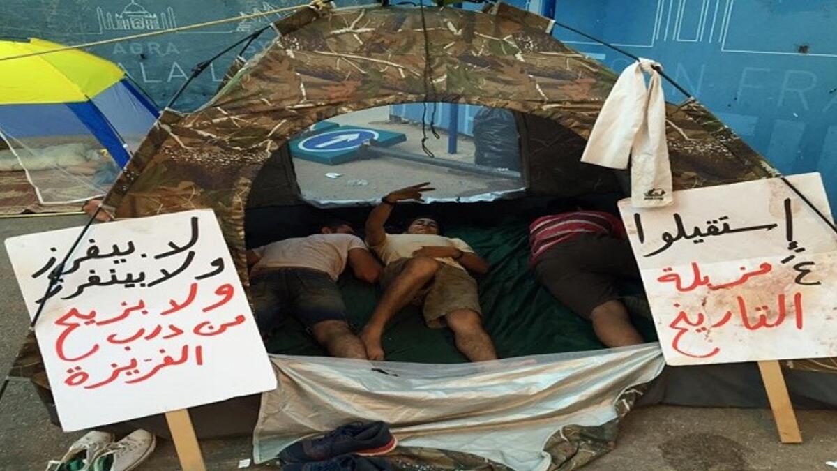 مجموعة من المتظاهرين يعتصمون داخل خيمة مطالبين الحكومة بالإستقالة تحت شعار "استقيلوا ع مزبلة التاريخ".