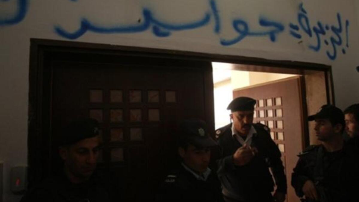 Palestinian security forces stand guard at the entrance of the Al-Jazeera offices in the West Bank city of Ramallah after some protesters stormed into the building and sprayed Arabic graffiti equating the pan-Arab news channel's staff to (Israeli) "spies".