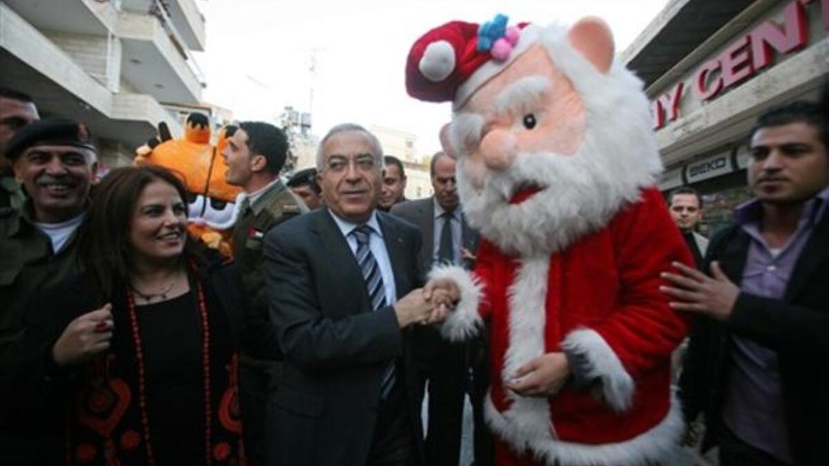 Palestinian prime minister Salam Fayyad (C) shakes hands with a man dressed as Santa Claus as he takes part in the 3rd annual march for unity and peace marking Christmas in the biblical West Bank town of Bethlehem.