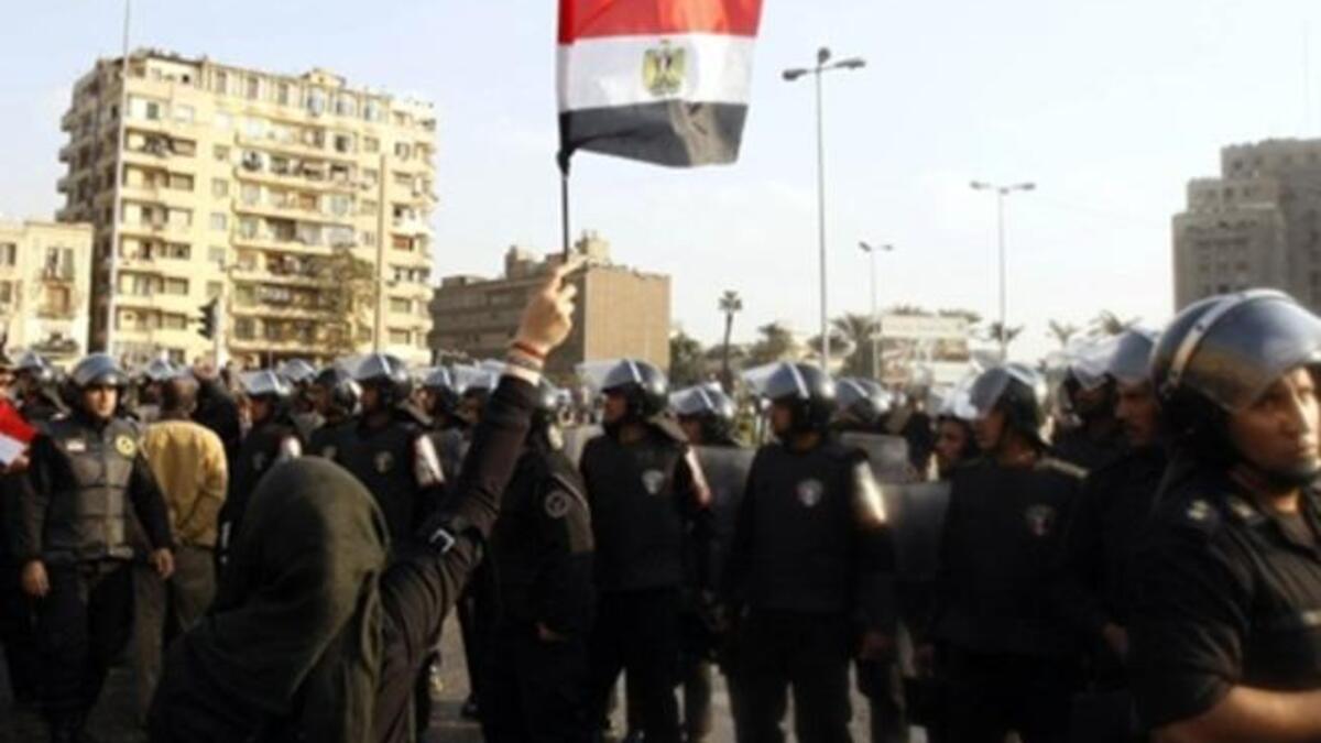 An Egyptian demonstrator holds up her national flag near the Egyptian police.