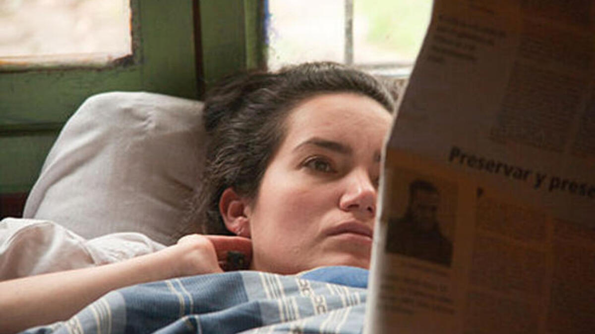 woman reading paper in bed