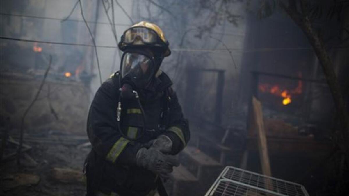 An Israeli firefighter stands at the site of a burning house in the village of Ein Hod, as the massive fire ripping through northern Israel was still incinerating swathes of land, with little sign that Israeli and foreign firefighters were winning the battle to contain it.