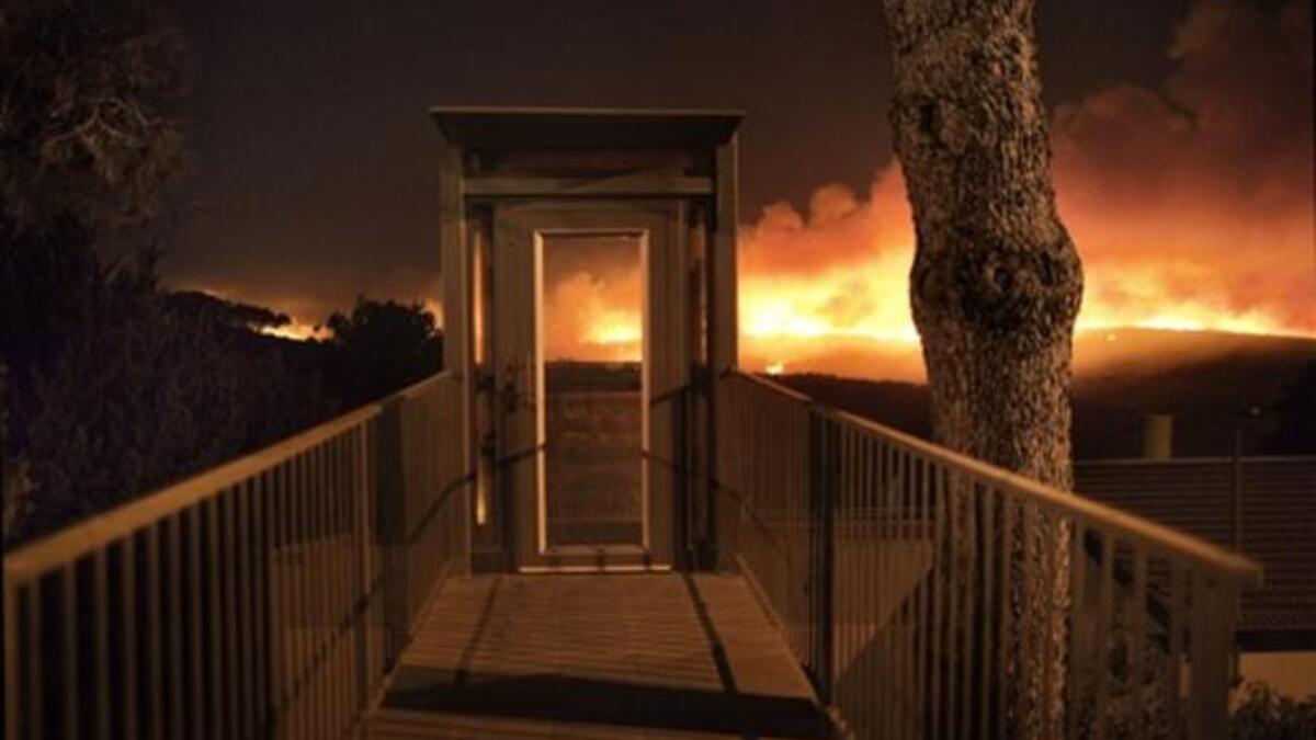 A forest fire rages out of control in front of a residential house  in the hills above the coastal Israeli city of  Haifa.