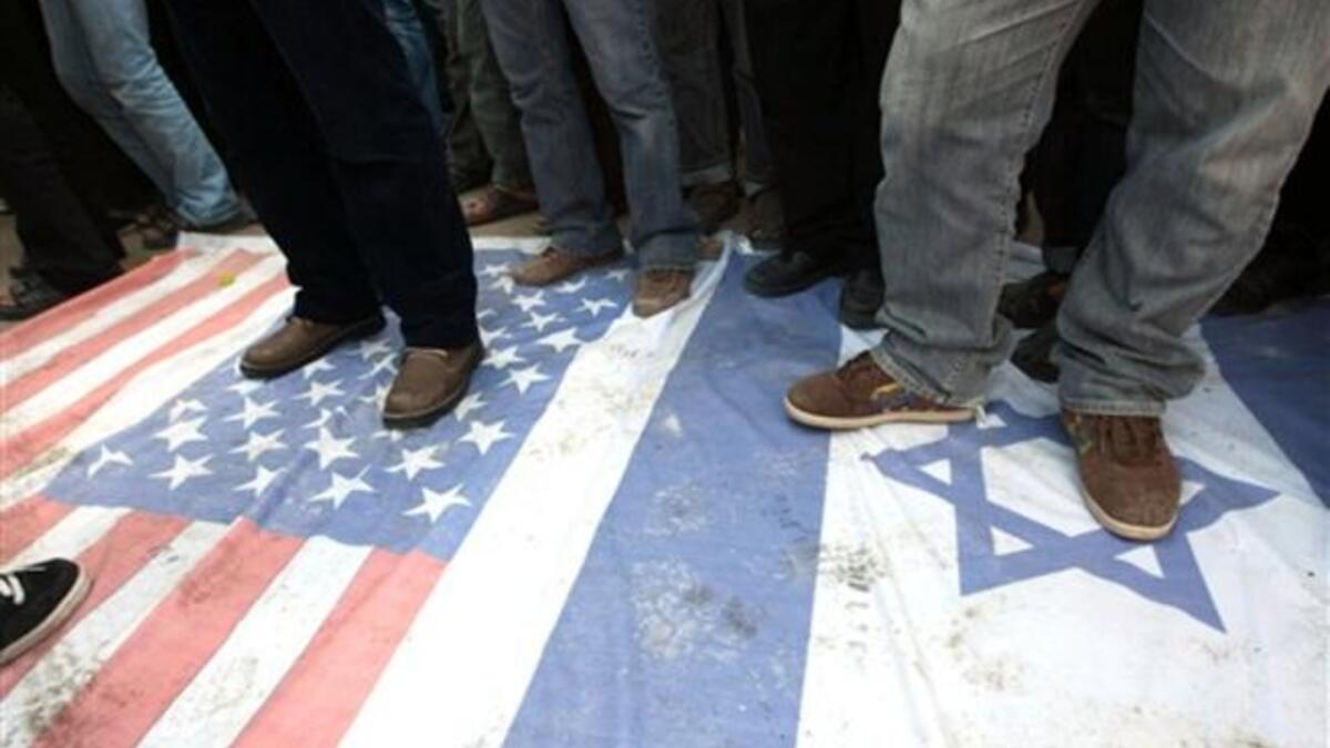 Islamic Jihad supporters walk at the USA and Israeli flag during a demonstration to mark the second anniversary of Israel's three-week offensive on the Gaza Strip.