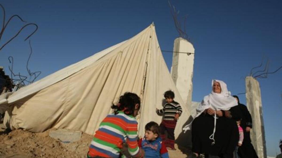 Members of a displaced Palestinian family sit outside their tent.