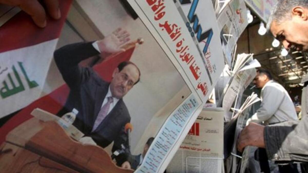Iraqis pick up newspapers featuring a front-page story on the country's new cabinet at a kiosk in Baghdad, a day after the Iraqi parliament gave Prime Minister Nuri al-Maliki's government a vote of confidence and adopted a 43-point program.