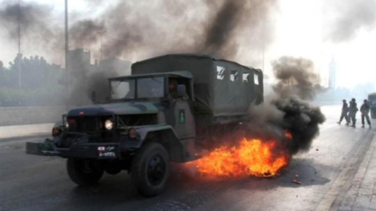 A Lebanese army truck drives through burning tires.