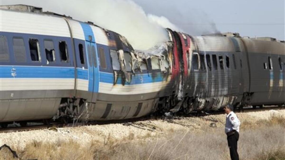 An Israeli policeman stands next to a burning train coach near Kibbutz Shfaim.