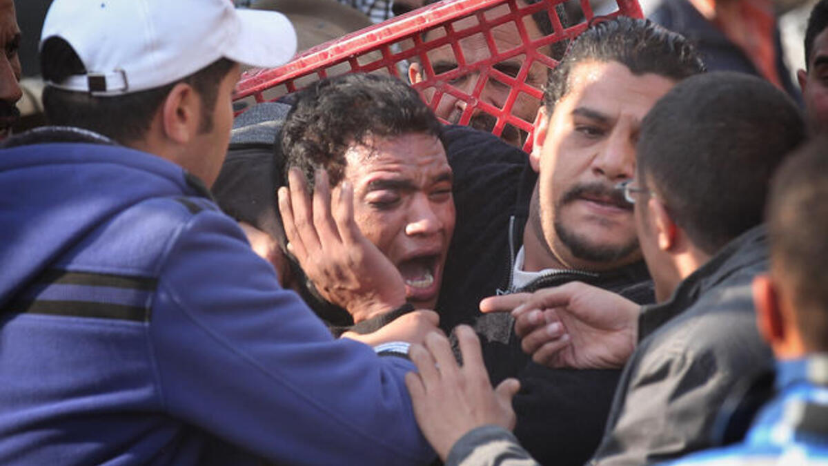 Anti-government protestors surround a supporter of President Mubarak after he was beaten in Tahrir Square.