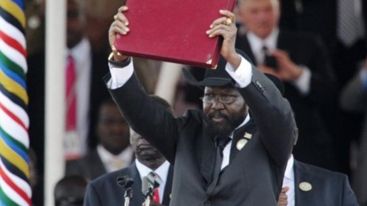 The President of Southern Sudan Salva Kiir waves the newly signed constitution of his country for the crowd to see.