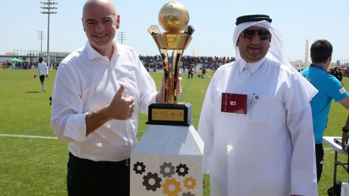 FIFA President Gianni Infantino (L) poses for a picture with the workers football cup trophy during a match ahead of a press conference in the Qatari capital Doha on April 22, 2016. 
KARIM JAAFAR / AFP