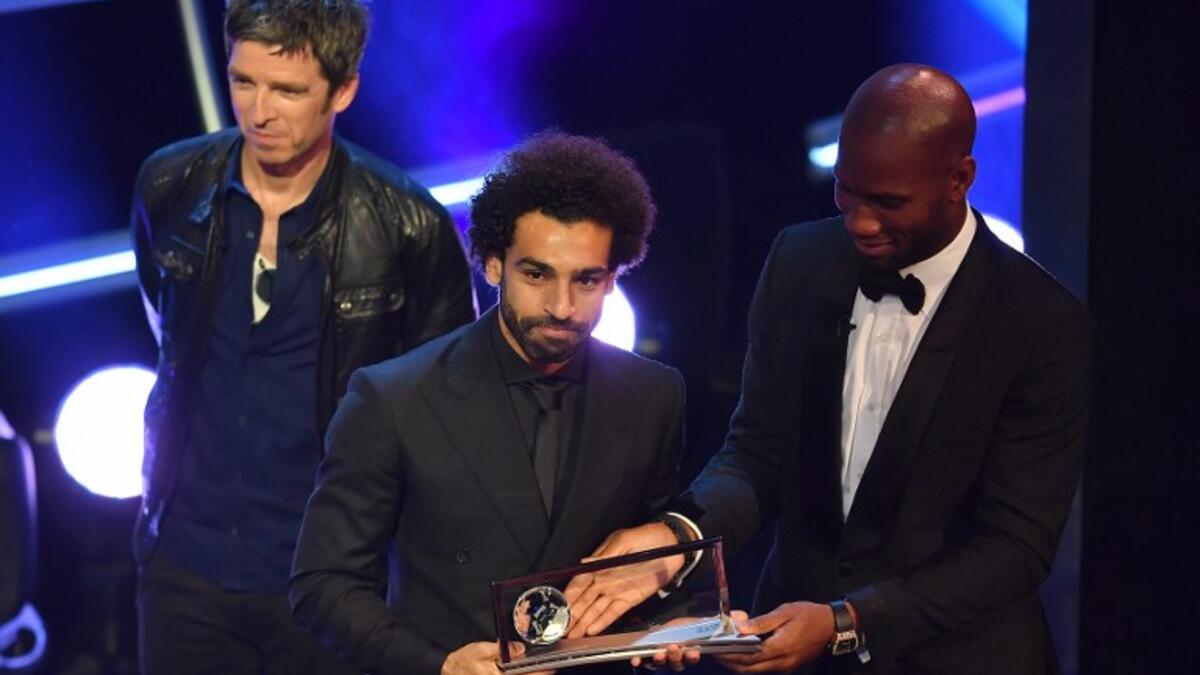 British singer-songwriter Noel Gallagher (L) and former Ivory Coast player Didier Drogba present Liverpool and Egypt forward Mohamed Salah (C) with the trophy for the FIFA Puskas Award for 2018, the best goal scored between July 2017 and July 2018 during The Best FIFA Football Awards ceremony, on September 24, 2018 in London. Ben STANSALL / AFP